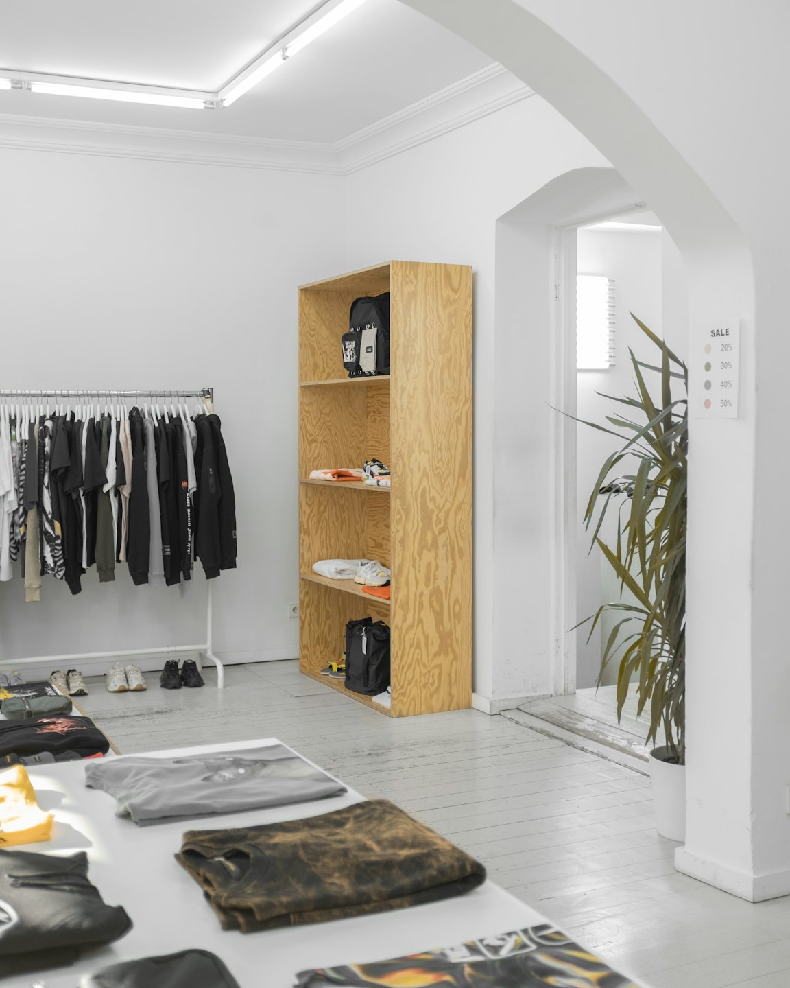 Interno di un negozio di abbigliamento minimalista con tavoli espositivi e scaffali.